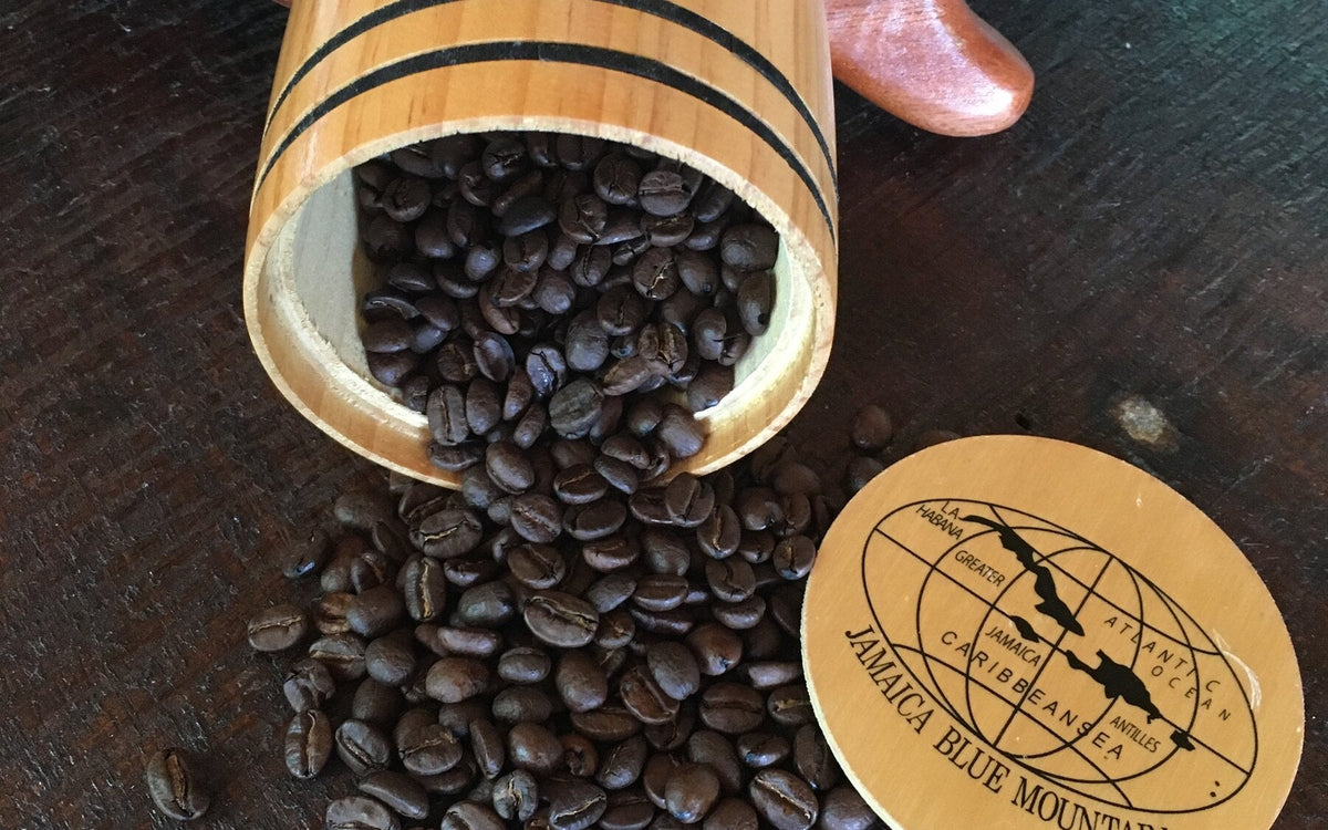 Roasted Jamaica Blue Mountain coffee beans spilling from a Wallenford wooden barrel